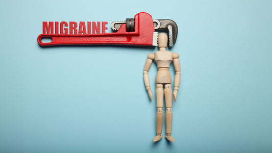 Vitamin B2 for migraines: Cure or Con? Wooden figure of man with his head clamped in vice with inscription migraine. 