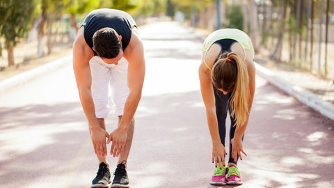 Best Joint Supplement 2024: Our Top Rated Products for Healthy Joints and Flexibility. Man and woman are in a park setting stretching and touching their toes.