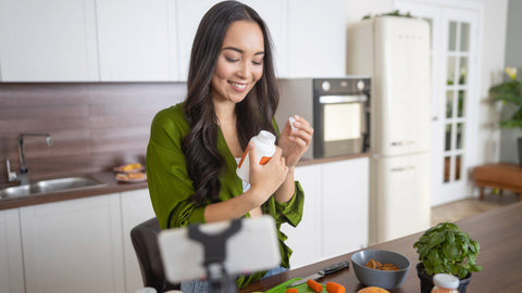 Smiling young lady looking at her vitamins. She is looking for the best low carb fiber supplement.