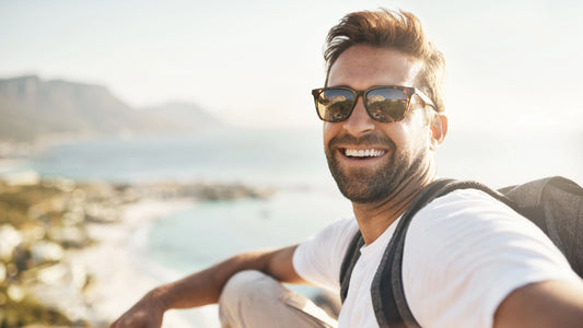 Best Multivitamin for Men 2024: Top Product for Peak Masculine Vitality and Health. A Healthy man in a white T-shirt smiles and takes a selfie against an ocean backdrop.