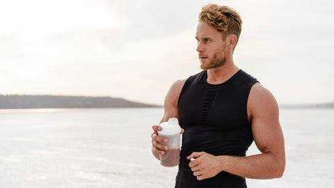 Best Zero Calorie Pre Workout. Healthy fit looking man exercising on a beach holding a zero calorie pre workout drink.