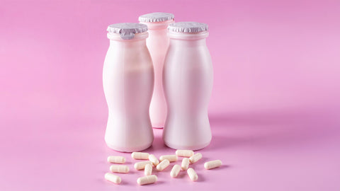 Can You Freeze Probiotics? Two bottles of milk yogurt (kefir) and capsules with probiotic on a pink background.