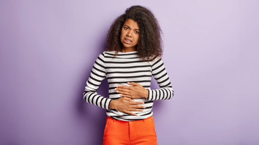 Can Vitamin B12 Cause Diarrhea? Woman in a striped top holding her stomach.