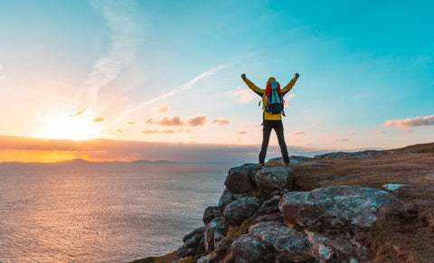 Research-Based Inositol benefits for Men. Happy successful man with arms up on the top of cliff at sunset.