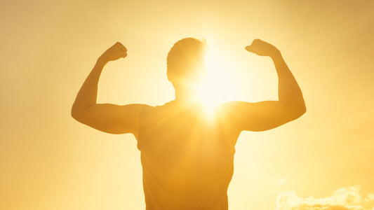 Unleash Masculine Vitality: Top Benefits of Vitamin D for Men. A healthy young man stands in the sunshine with arms raised.
