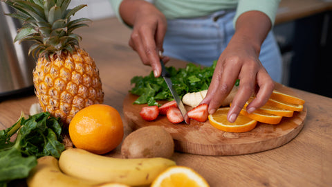 A close up of young woman cutting strawberry and fruit for a smoothie. Vitamin C for IBS: What Effect Does It Have?