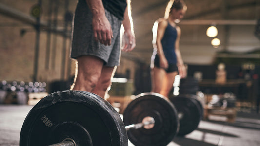 Kre-Alkalyn Vs creatine Monohydrate: Which is The Best Creatine? Muscular, fit male and female in the gym, ready to lift a heavily weighted barbell.